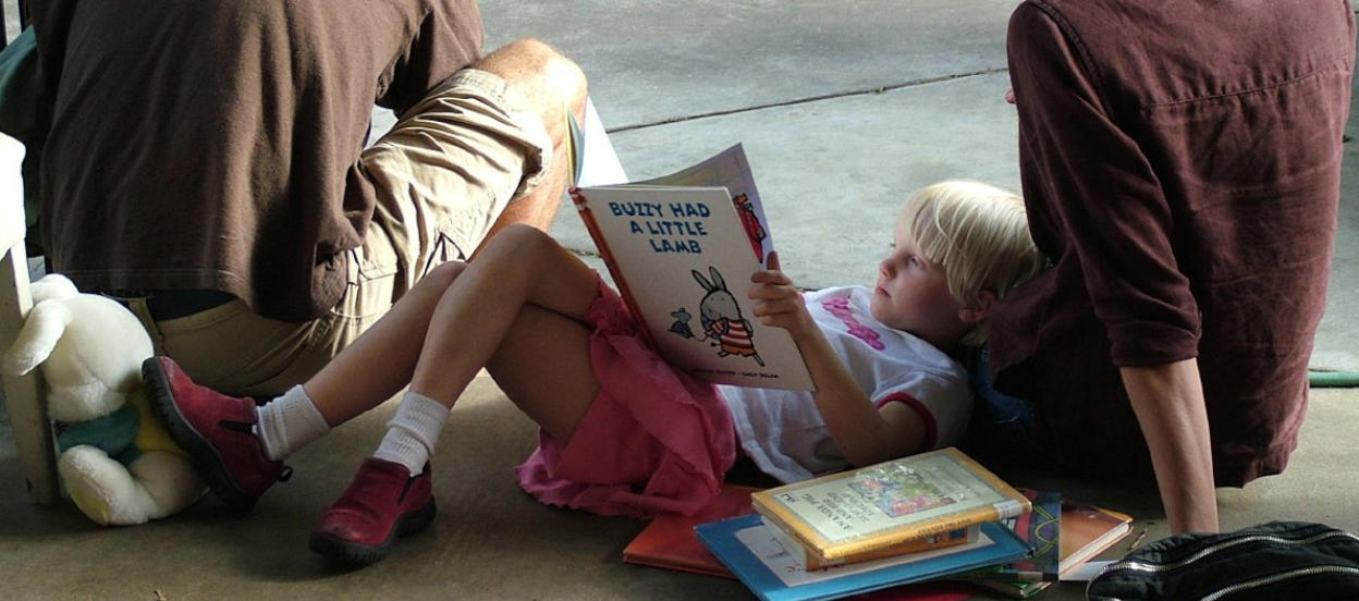 Child waiting for train with story book