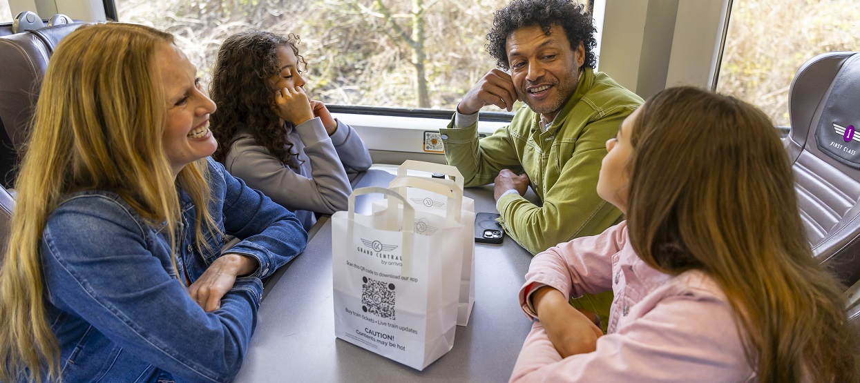 a family sat talking on a table seat of a train