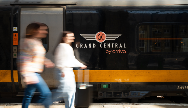Two women walking with a suitcase on the train station platform 