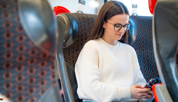 Girl sat on the train looking at her mobile phone