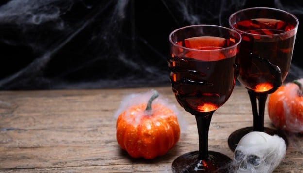 Two glasses of drink next to Halloween pumpkins
