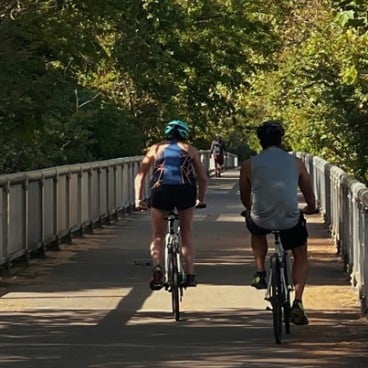 two people riding bikes over a bridge in a park 