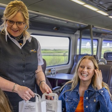 member of staff serving customers on a train with a bag of food