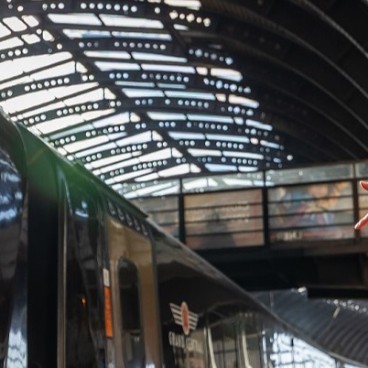 couple smiling and pointing at Grand Central train whilst boarding